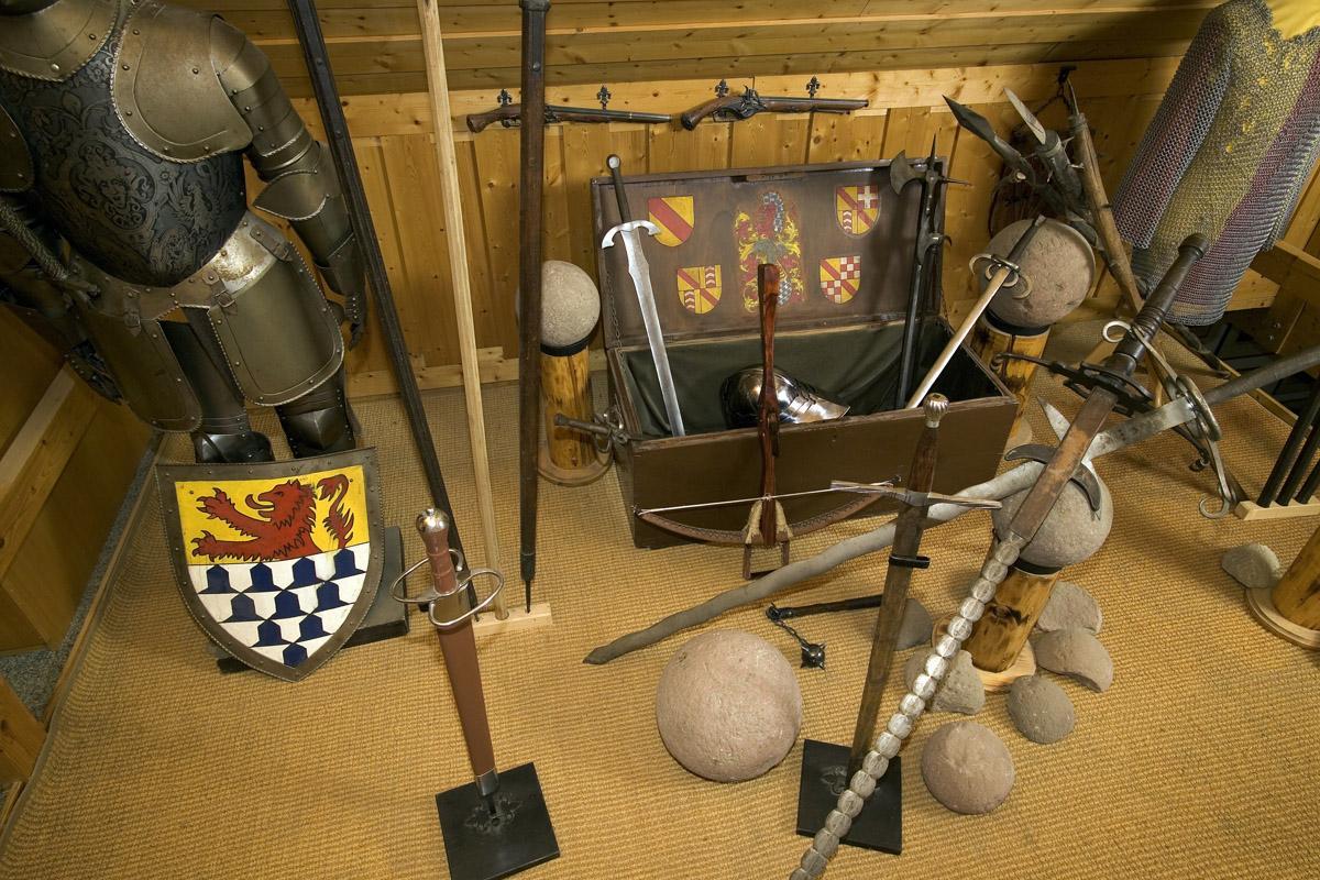 Burg Rötteln, Burgmuseum, Funde (Kanonenkugeln, Stein) aus dem Bereich der Burg Rötteln neben Rüstung und Wappenschild